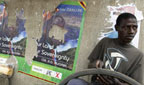 Tyre fixer next to Mugabe posters in Harare